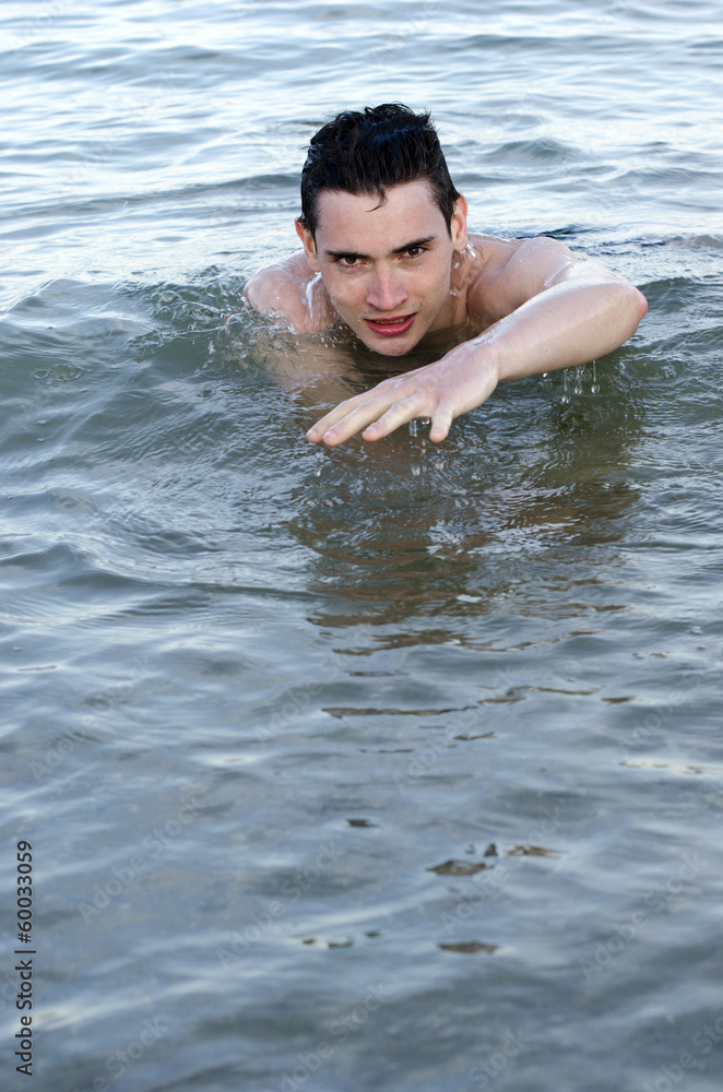 Young man trying to survive in water and learning to swim
