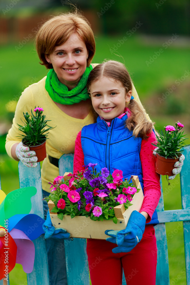 Gardening, girl with mother working in flowers garden