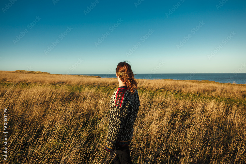 Young woman standing in meadow by the sea