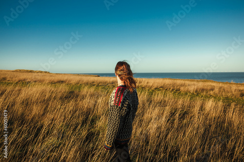 Young woman standing in meadow by the sea