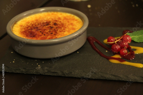 Postre de crema catalana con frutas del bosque servida sobre tabla de piedra photo