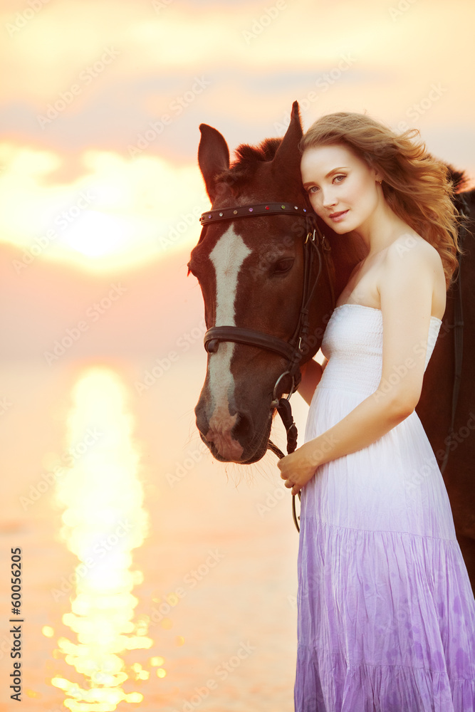 Obraz premium Beautiful woman riding a horse at sunset on the beach. Young gir