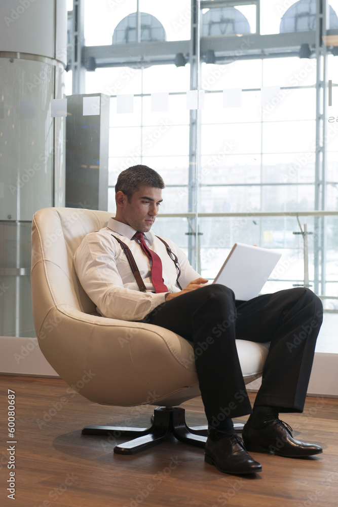 Businessman in arm chair working on laptop Businessman in arm chair working on laptop
