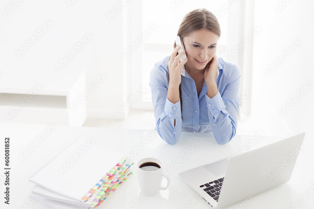 Woman using cell phone and looking at computer Woman using cell phone and looking at computer