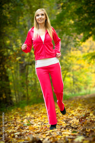 Fototapeta Naklejka Na Ścianę i Meble -  Woman running in autumn forest.  Female runner training.