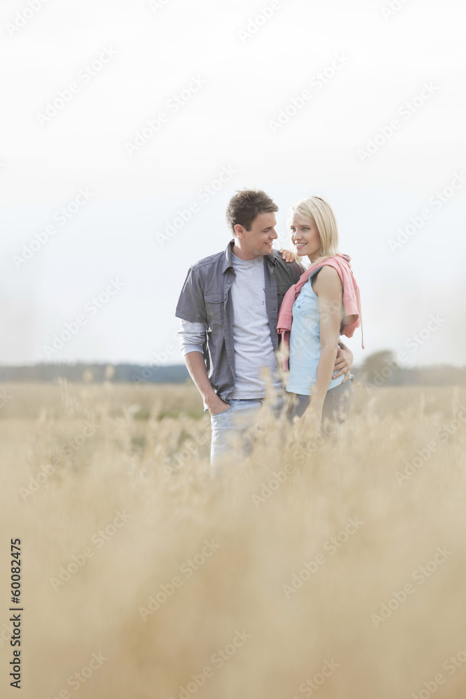 Happy loving young couple standing together at field Happy loving young couple standing together at field