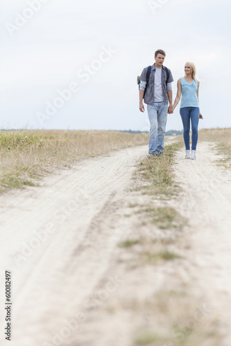 Full length of young hiking couple walking on trail at field © moodboard