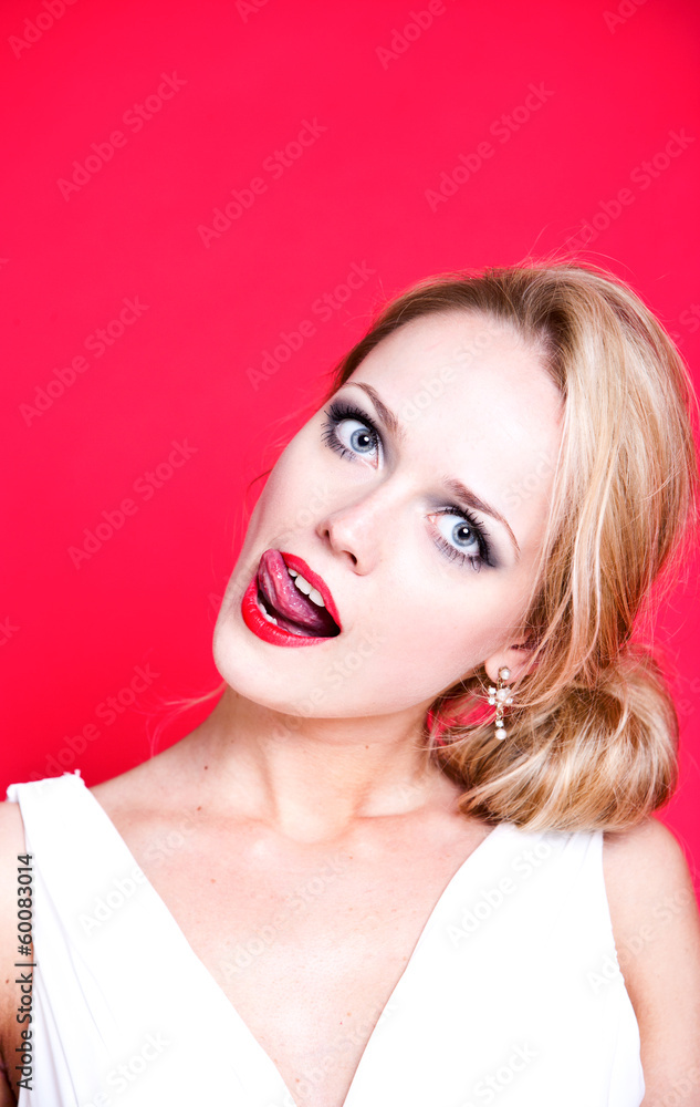 Caucasian woman wearing white dress on red background licking her lips Caucasian woman wearing white dress on red background licking her lips