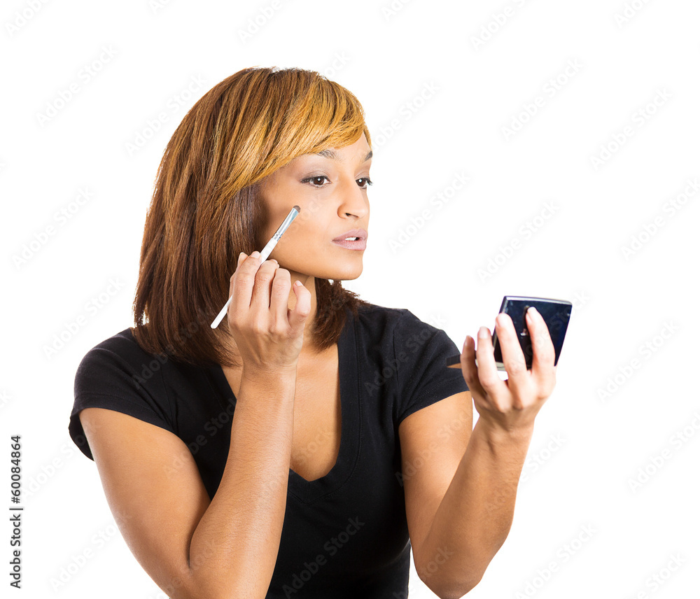Woman applying make up looking in a pocket mirror Woman applying make up looking in a pocket mirror