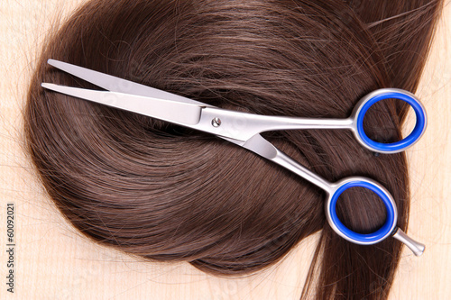 Long brown hair and scissors on wooden background