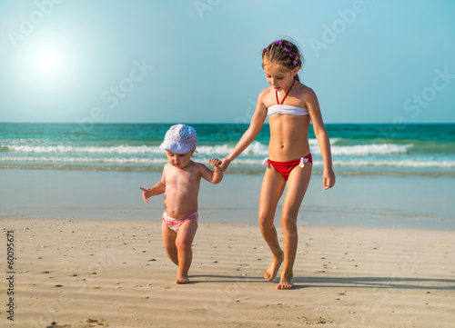 Fotografie little sisters walking along the beach