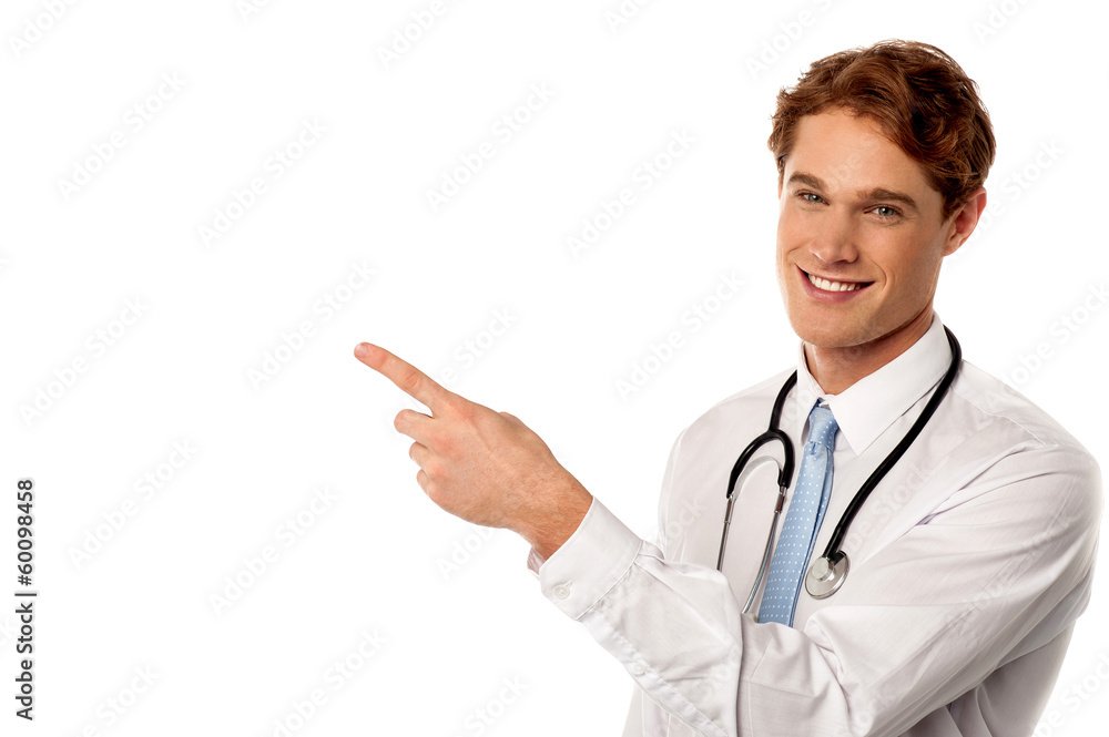 Smiling young physician pointing away Smiling young physician pointing away