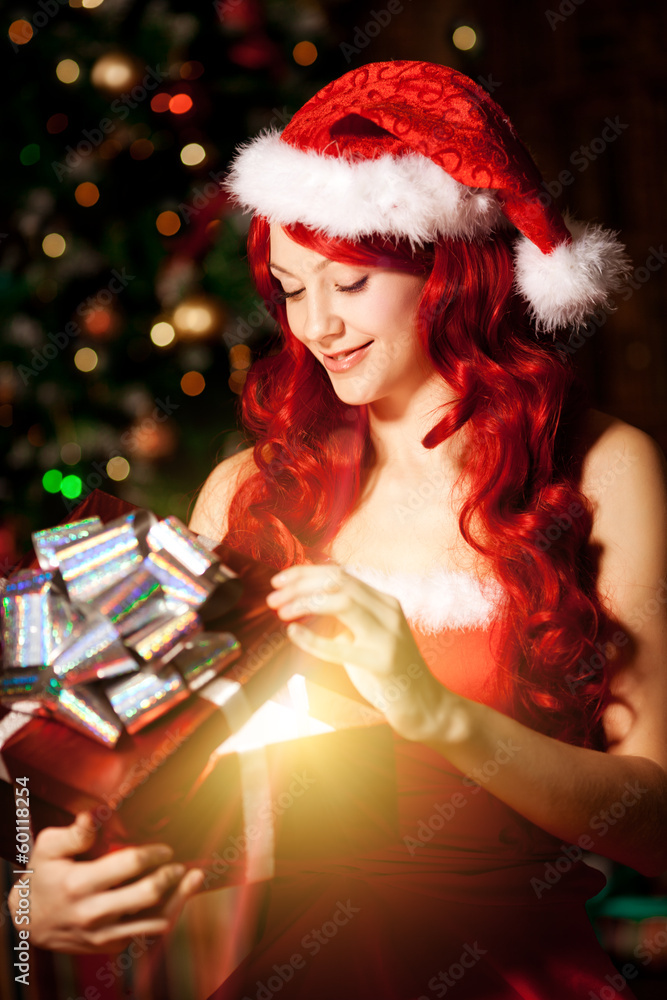 Young beautiful smiling santa woman near the Christmas tree with
