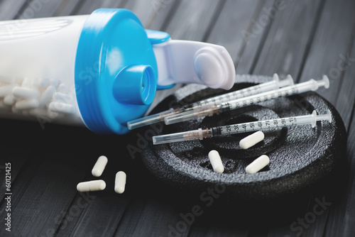 Fotografija Shaker with tablets, syringes and weight disk, close-up