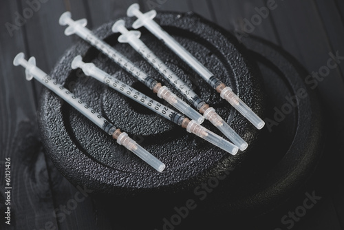 Close-up of syringes on weight plates, horizontal shot