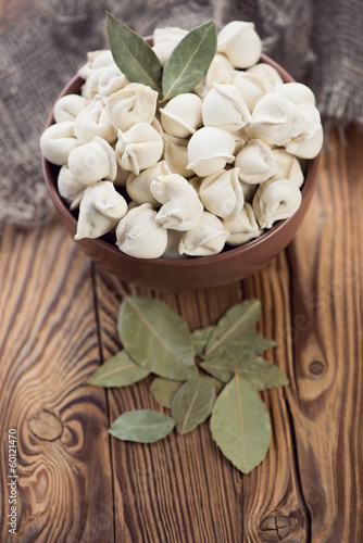 Raw pelmeni with dried bay leaves  vertical shot
