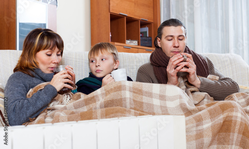 freezing family of three   warming near warm radiator photo