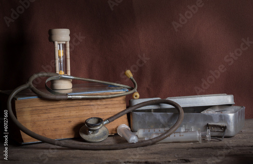 Hourglass and book with old medical tools.