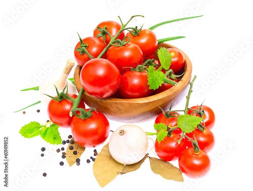 The branch of cherry tomatoes in a wooden bowl, onion, garlic, b