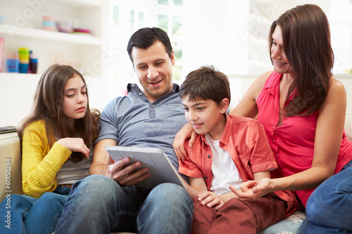 Hispanic Family Sitting On Sofa Using Digital Tablet