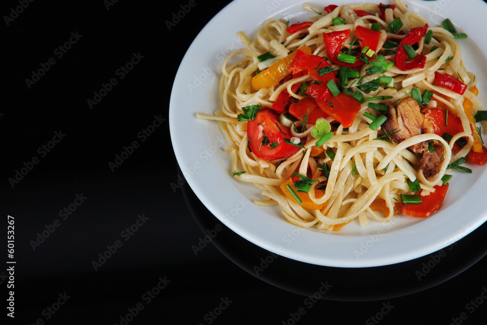 Noodles with vegetables on plate isolated on black Noodles with vegetables on plate isolated on black