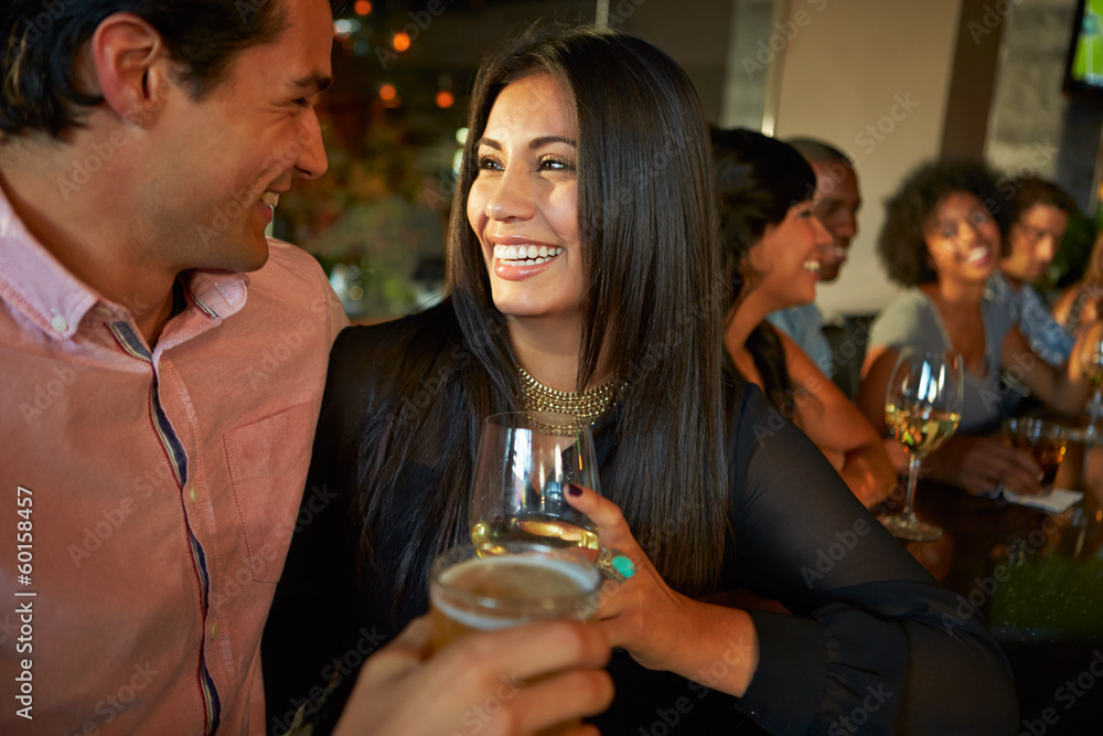 Couple Enjoying Drink At Bar With Friends Couple Enjoying Drink At Bar With Friends