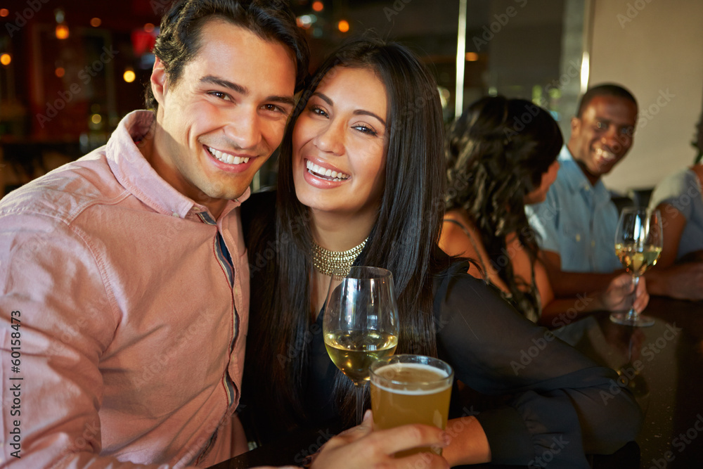 Couple Enjoying Drink At Bar With Friends