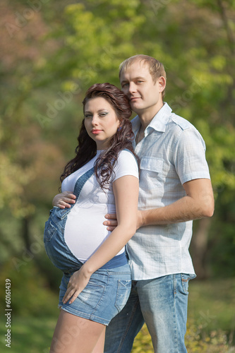 Young man with his pregnant wife posing on open air © azazello