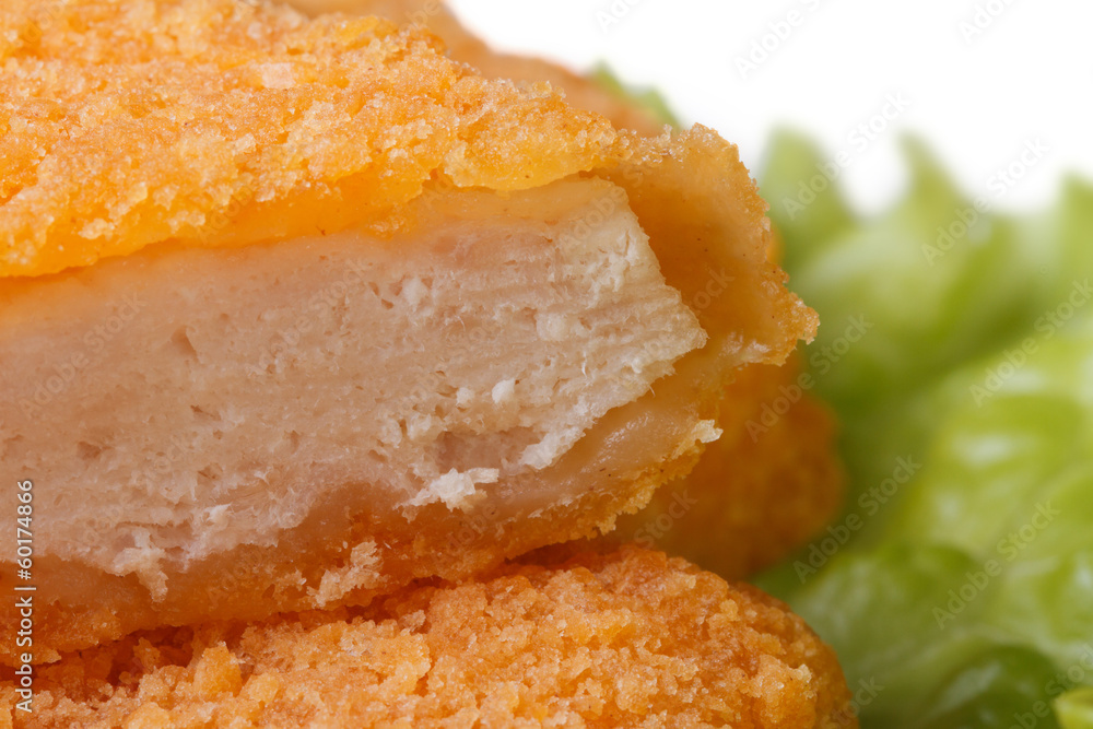 Fresh chicken nuggets cut into green lettuce close up. macro Fresh chicken nuggets cut into green lettuce close up. macro