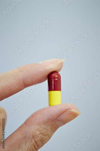 Hand holding a pill isolated on white