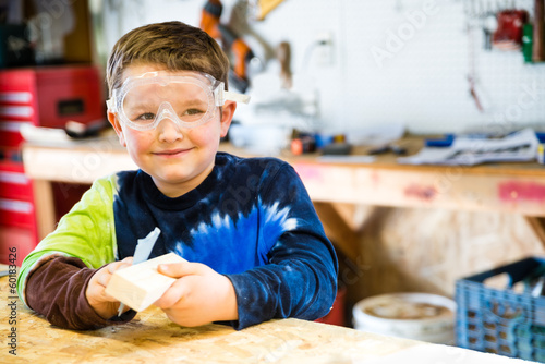 Принти на полотні Boy sanding wooden block as he builds car for Pinewood Derby