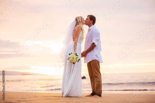 Married couple, bride and groom, kissing at sunset on beautiful
