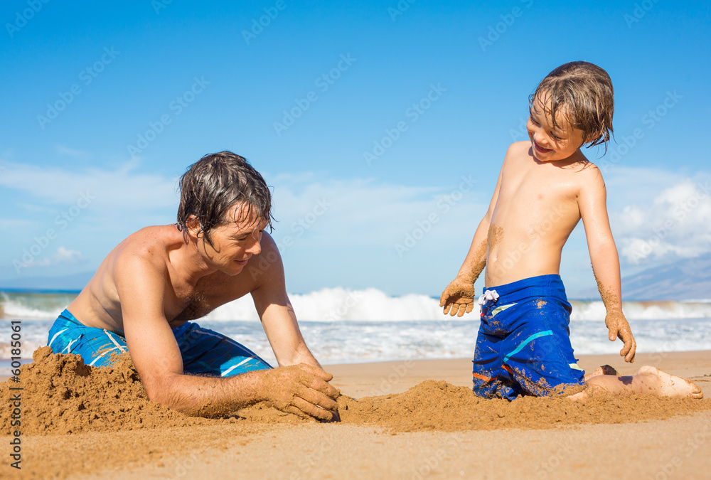 Father and son playing together in the sand on tropical beach Father and son playing together in the sand on tropical beach