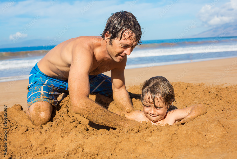 Father and son playing together in the sand on tropical beach Father and son playing together in the sand on tropical beach