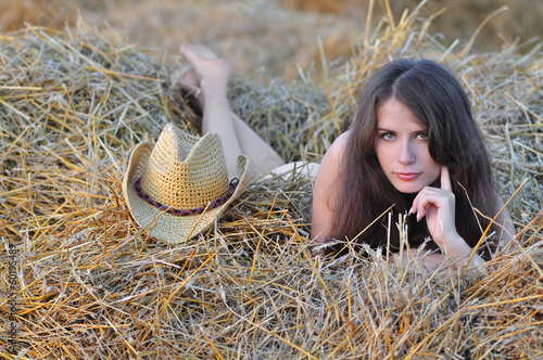 Slika na platnu Nude girl lies on senovalle near cowboy hat