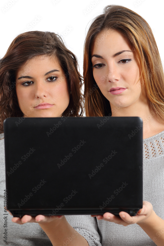 Two teenager girls bored watching a netbook computer Two teenager girls bored watching a netbook computer