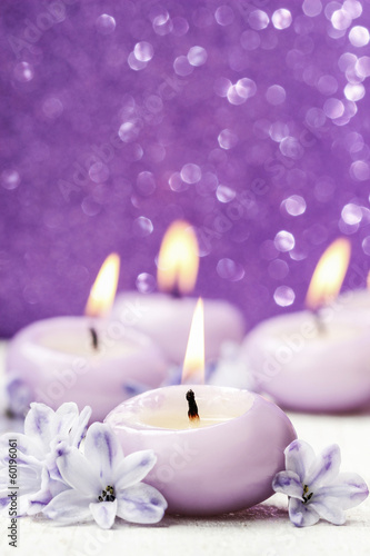 Scented candles and hyacinth flowers on violet background