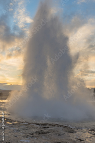 Eruption of Strokkur Geyser against setting sun in Iceland