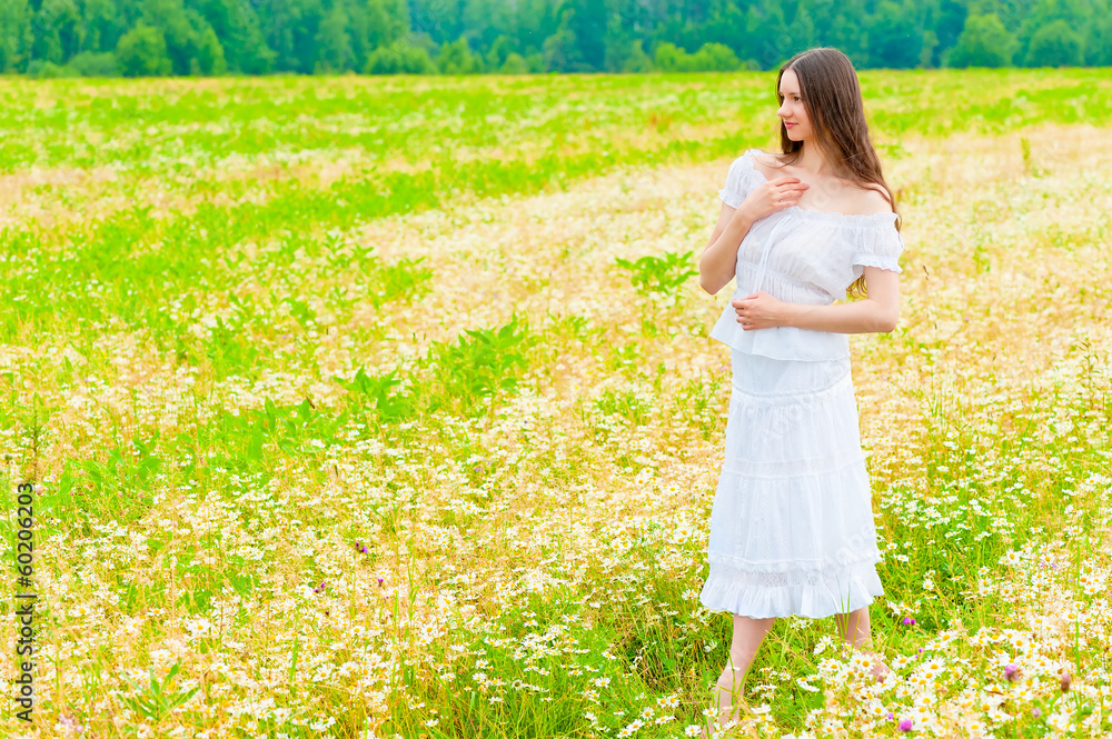 girl in a white sundress walking on chamomile field girl in a white sundress walking on chamomile field