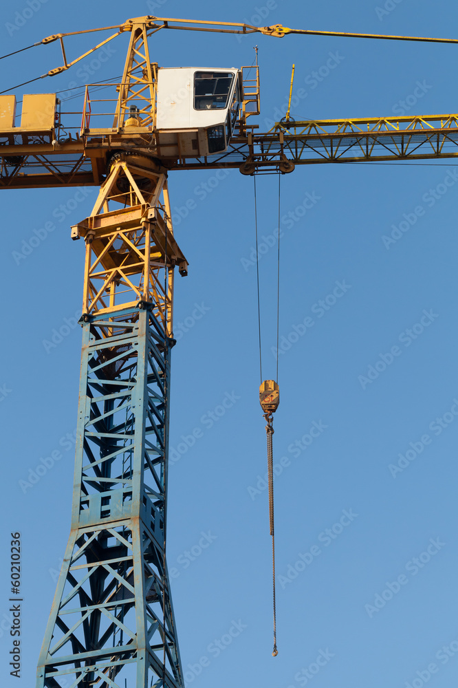 Blue and yellow tower crane fragment above blue sky Blue and yellow tower crane fragment above blue sky