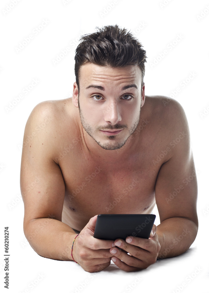 Fototapeta premium Handsome young man shirtless reading ebook on the floor