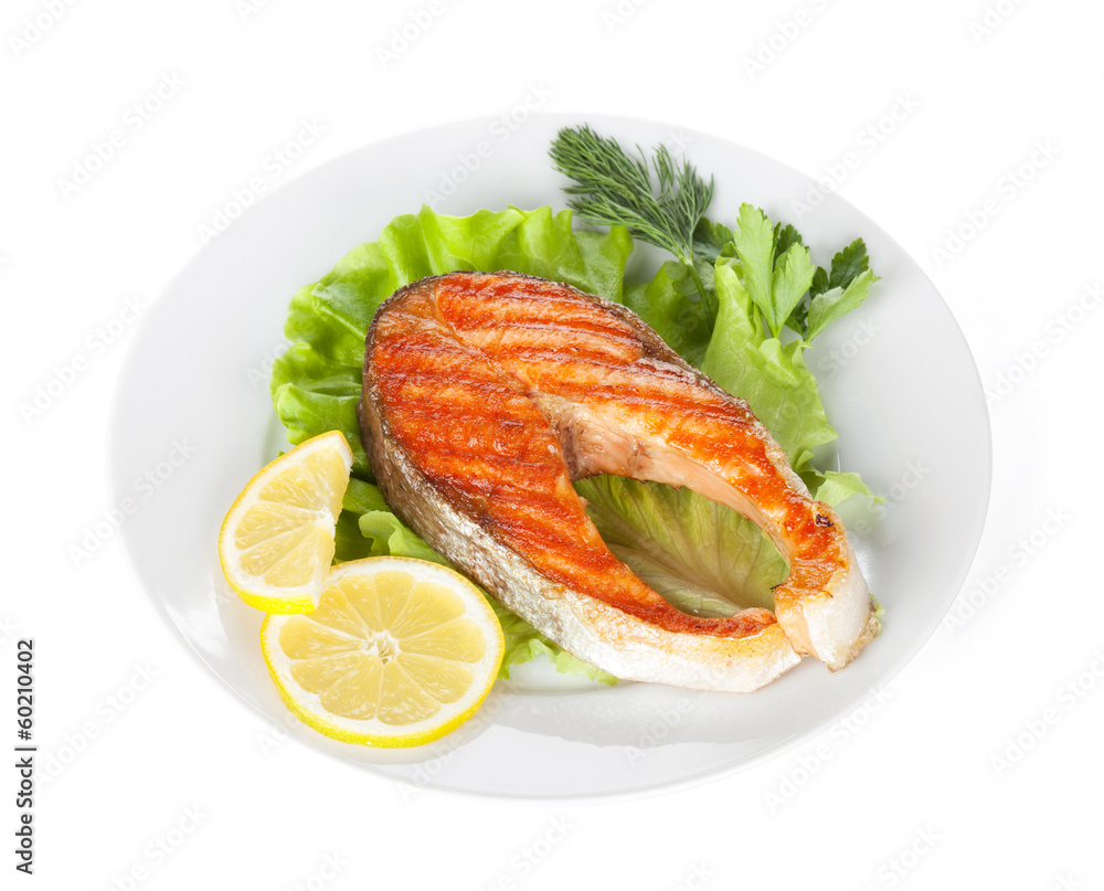 Grilled salmon with lemon slices and herbs on plate Grilled salmon with lemon slices and herbs on plate