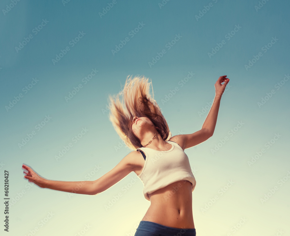 Blonde teenager girl jumping happy with the blue sky in the back Blonde teenager girl jumping happy with the blue sky in the back