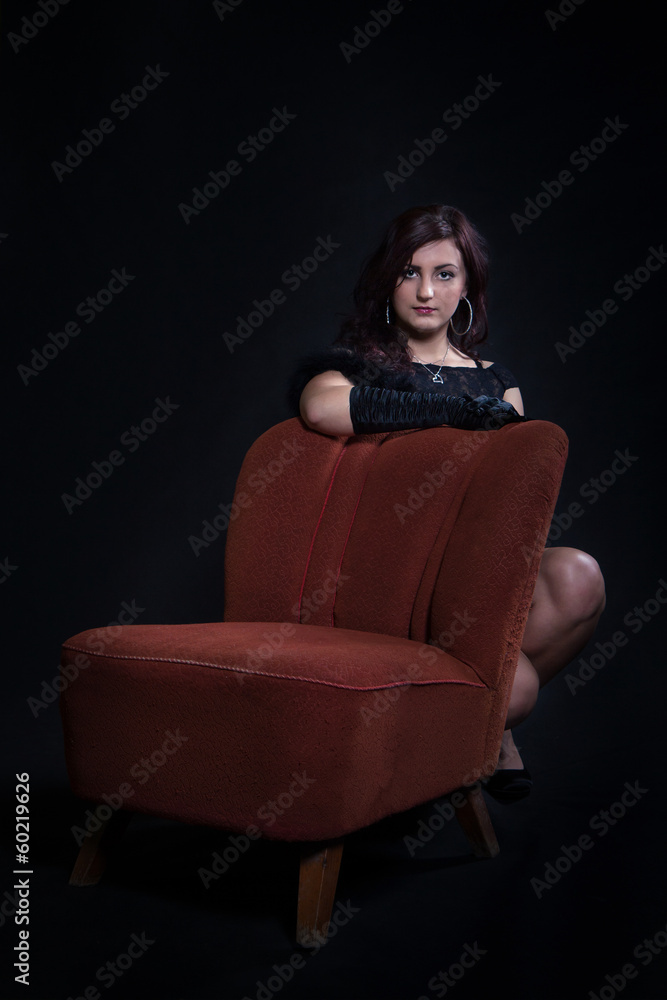 Young woman in retro clothing on old orange chair Young woman in retro clothing on old orange chair