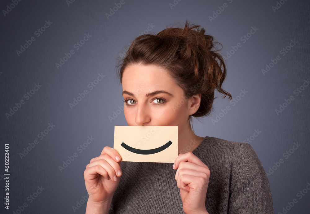 Happy pretty woman holding card with funny smiley Happy pretty woman holding card with funny smiley