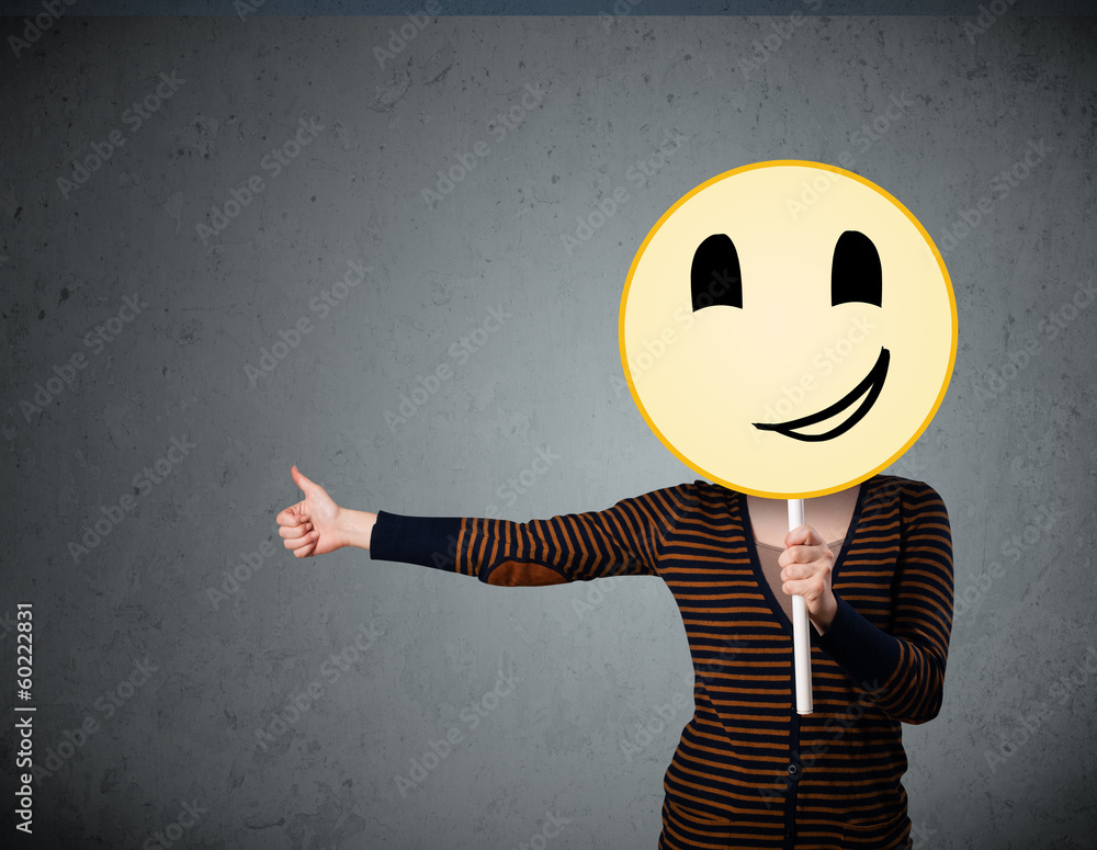 Young woman holding a smiley face emoticon Stock-Foto | Adobe Stock