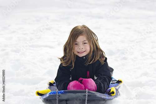 Canvas Print Cute Little Girl going snow sledding down a hill