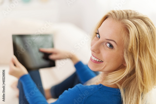 Relaxed woman sitting on sofa with digital tablet