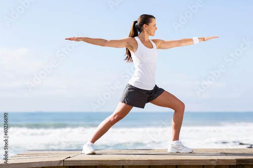 young woman doing yoga on beach