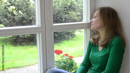 sad worried woman sits on window sill. photo